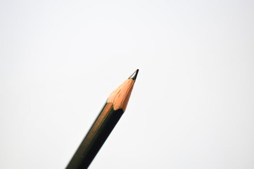 green pencil sharpener and dark green pencils, pencil shavings on white background photo
