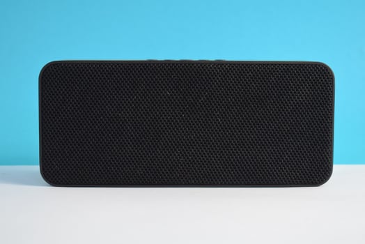 Wireless black Speaker box for play music on blue background, Wireless Music player, electronic. photo