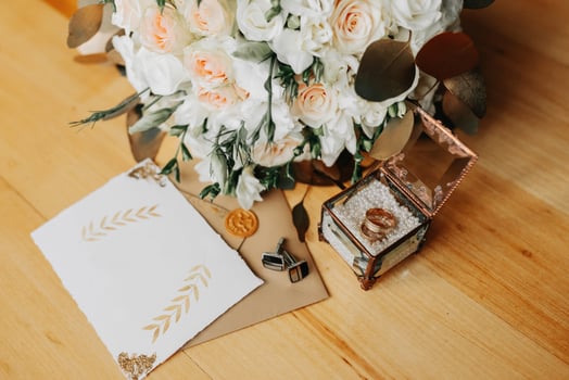 Accessories for the groom's wedding. Luxurious bouquet of the groom. Golden wedding invitation, golden rings, cufflinks on wooden floor background. Men's fashion photo