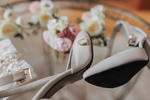 Top view, wedding boutonnieres for groom and groomsmen and bride's shoes on glass background. Emphasis on the wedding ring, which is on the shoes. Wedding details. Preparation of the wedding morning photo