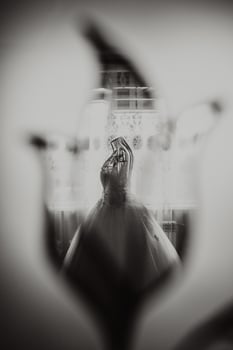 An exquisite wedding dress on a mannequin in the bride's room with a royal interior. Photo reflection in the mirror. Black and white photo