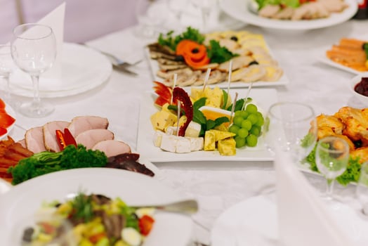 buffet table at a wedding. Cheese plate. Assortment of canaps. Banquet service. food, snacks with cheese, ham, prosciutto and fruit. Caesar salad. Glass glasses. Silver table sets. photo