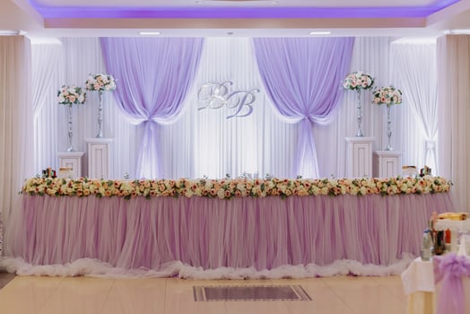 The wedding table of the bride and groom, decorated with flowers, is made in purple. Flowers on stands. Wedding details photo