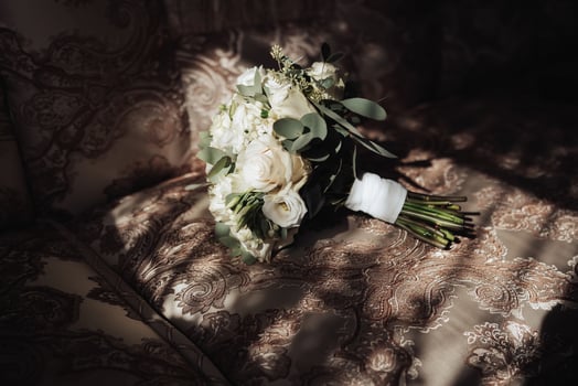 Accessories for the groom's wedding. A bouquet of white roses and greenery stands on the back of the sofa near the window. Beautiful flowers. Light and shadows photo