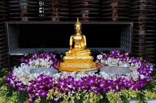 Gold Budda statue decorate surrounded variety color orchids for pouring water on table outdoor in Songkran festival in Thailand. photo
