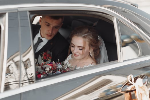 A modern bride and groom in a lace dress in a car window. Beautiful and smiling newlyweds. Happy holiday. photo