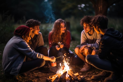 AI generated Group of young friends sitting near bonfire at night Camping concept, Young people sitting around a bonfire Ai generated photo