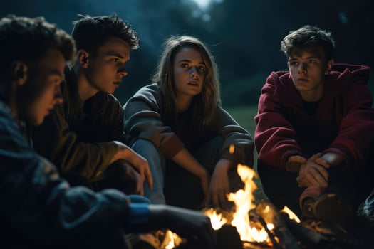 AI generated Group of young friends sitting near bonfire at night Camping concept, Young people sitting around a bonfire Ai generated photo