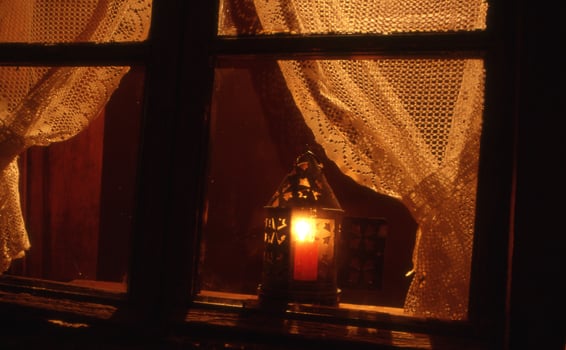 a candle lit by a lantern in a window photo
