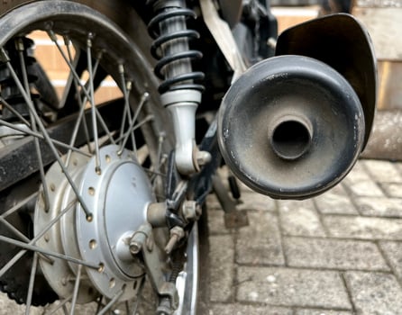 Motorbike or motorcycle vehicle exhaust part, smoke hole view. Transportation themed photo isolated on brick ground flooring.