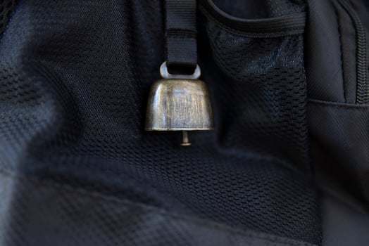 A backpack with bear bell at the green forest in Autumn closeup photo