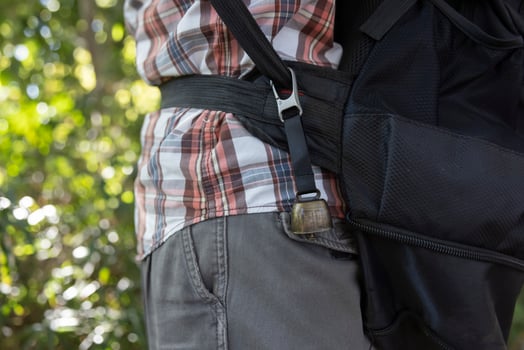 A person who wear a backpack with bear bell at the green forest in Autumn photo