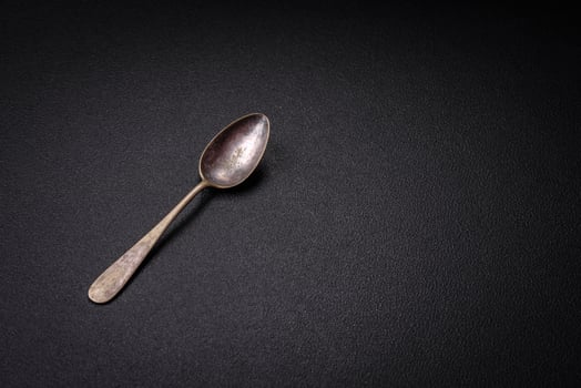 Empty metal spoon on dark textured concrete background photo
