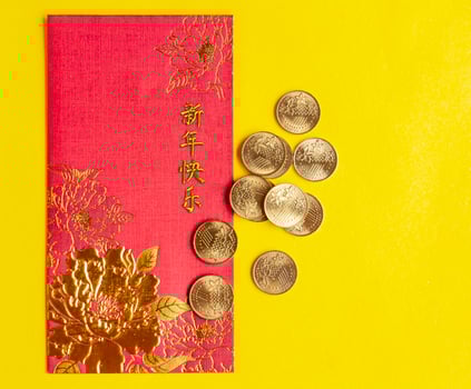 Top view of Chinese New Year red packets on yellow cover background. Customizable space for text photo