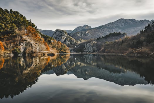 AI generated a serene and picturesque landscape of a calm lake surrounded by mountains. The mountains are rugged and partially covered with greenery photo