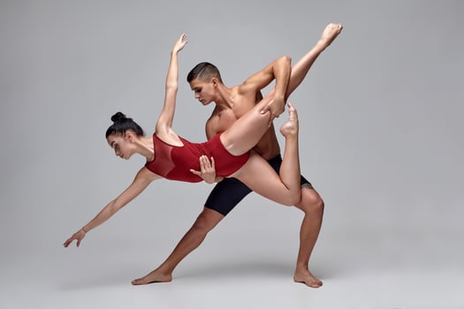 The couple of an athletic modern ballet dancers are posing against a gray studio background. photo