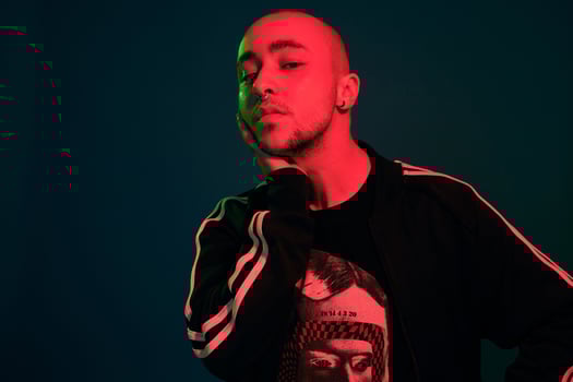 Studio shot of a young tattoed bald man posing against a colorful background. 90s style. photo