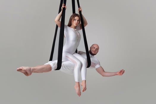 Beautiful girl and an athletic man in a white sport suits are performing an acrobatic elements in a studio. photo