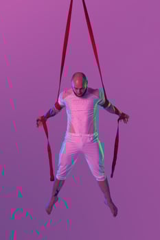 Athletic man in a white sport suit is performing an acrobatic elements in a studio. photo