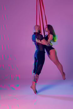 Beautiful girl and an athletic man in a black sport suits are performing an acrobatic elements in a studio. photo