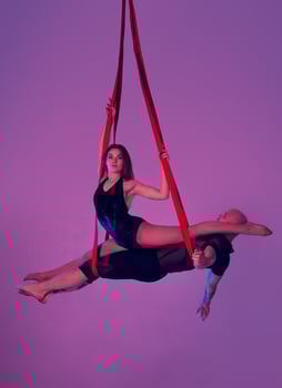 Beautiful girl and an athletic man in a black sport suits are performing an acrobatic elements in a studio. photo