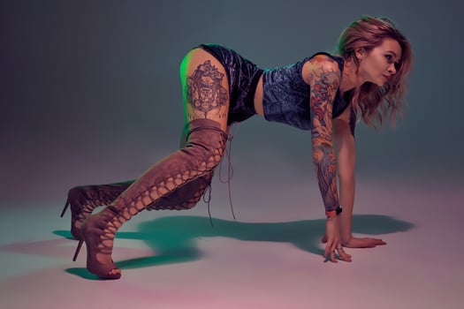 Sexy blond woman with tattoed body and long curly hair is dancing twerk in studio. photo