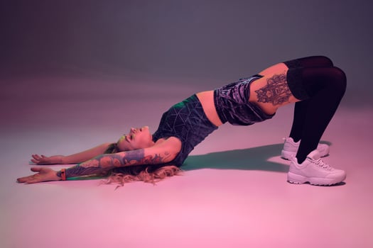 beautiful caucasian blonde girl in velour blue booty shorts and black stockings does exercises on pink background photo