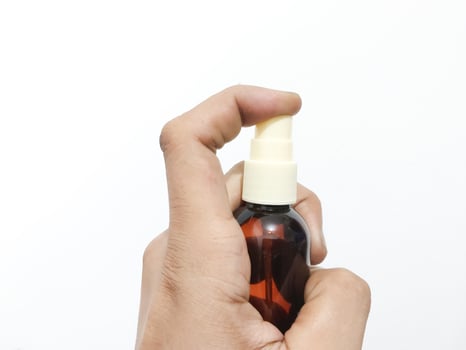 fingers holding or grasping a spray bottle isolated on a white background photo
