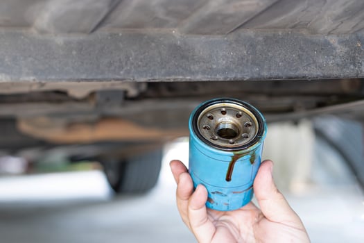 Close up hand a man hold old oil filter and remove from under car on lift for car maintenance concept photo