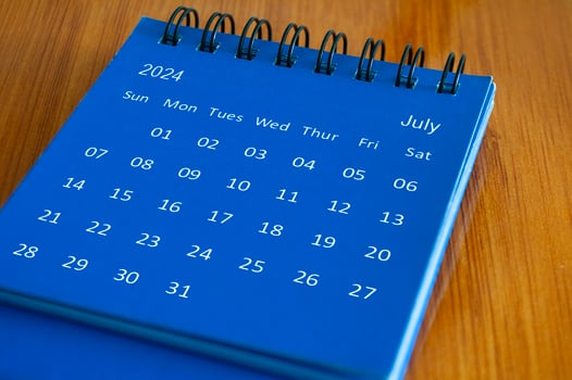 July 2024 table calendar on wooden desk. Time and calendar concept photo
