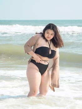 Portrait young asian woman fat chubby cute beautiful smile happy fun bikini swimwear body sexy front view tropical sea beach white sand clean and bluesky calm nature ocean wave water travel on holiday photo