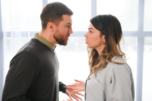 Boyfriend and girlfriend are arguing at home. Angry man is yelling at his sad girlfriend photo