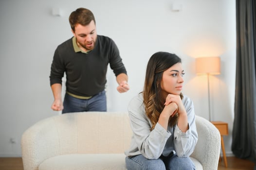 Boyfriend and girlfriend are arguing at home. Angry man is yelling at his sad girlfriend photo