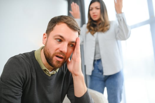 Couple arguing. Wife shouting to her desperate husband sitting on a couch in the living room at home photo