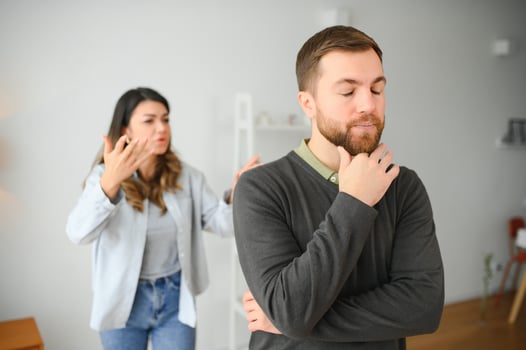 Couple arguing. Wife shouting to her desperate husband sitting on a couch in the living room at home photo