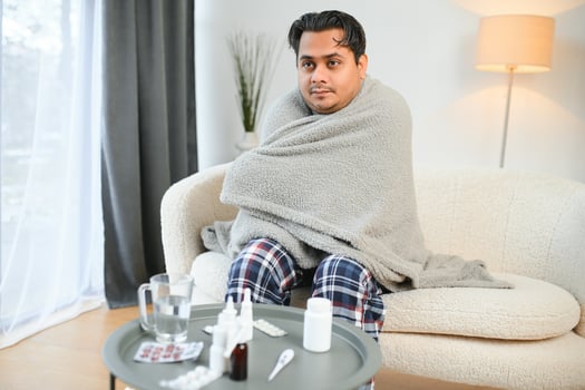 Sick Indian man in plaid sit alone shivering from cold. Unhealthy Arabian guy sit on chair feeling discomfort try to warming up photo