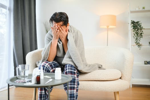 health, cold and people concept - sick young indian man in blanket having headache or fever at home photo