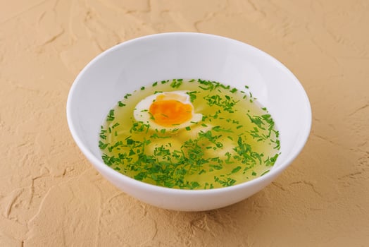 Chicken soup with egg and dill in white bowl photo