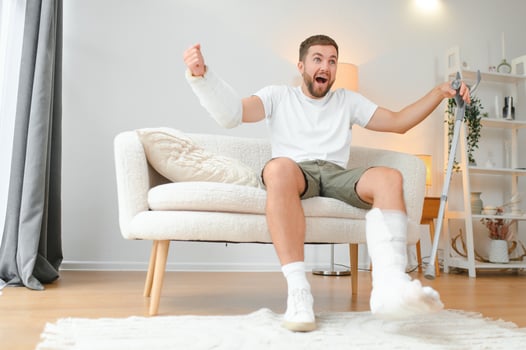 Man with multiple physical limb and body injuries recovers after accident. Happy guy having fun at home photo
