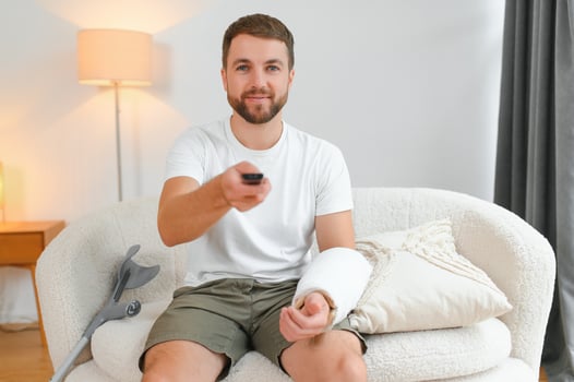 Young man after car accident suffering at home. A man with injuries is watching TV photo