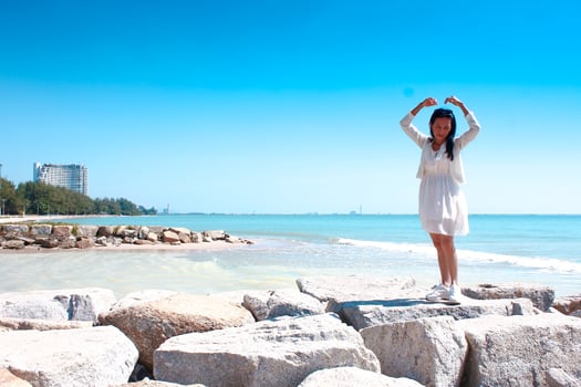 Beautiful asian woman in white dress standing on the beach and looking at the sea photo