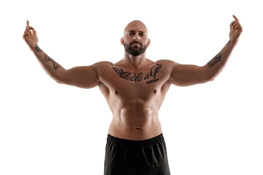 Athletic bald, tattooed man in black shorts is posing isolated on white background. Close-up portrait. photo