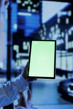 Person having fun walking around city at night, scrolling on social media using mockup tablet, close up. Citizen using green screen device while strolling in empty metropolitan setting photo