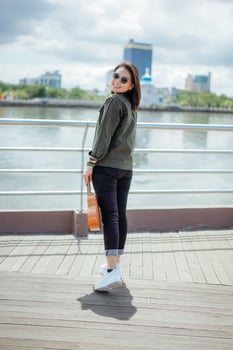 Playing Ukulele of Young Beautiful Asian Woman Wearing Jacket And Black Jeans Posing Outdoors photo