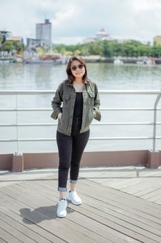 Young Beautiful Asian Woman Wearing Jacket And Black Jeans Posing Outdoors photo