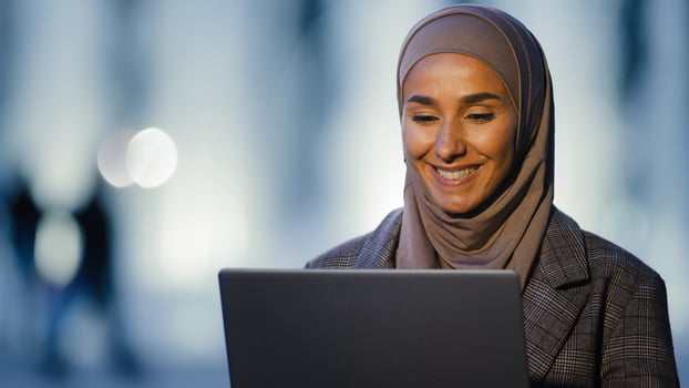 Portrait ethnic islamic muslim business woman girl international student speaks video chat conference using laptop talking in web camera sitting in evening night on street in city remote conversation photo