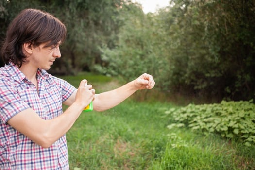 Young man spraying mosquito insect repellent in the forrest, protection photo
