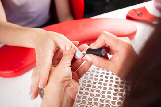The manicurist holds hands of the client in beauty salon on desktop for manicure with nail polishes, napkins, creams and lighting instruments photo