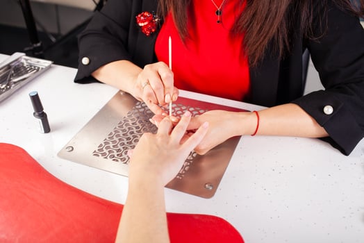 The manicurist holds hands of the client in beauty salon on desktop for manicure with nail polishes, napkins, creams and lighting instruments photo