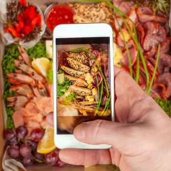 a man takes pictures of food on his phone. Shrimp, snack, fruit, meat, vegetables. A picture of food on your phone screen. photo